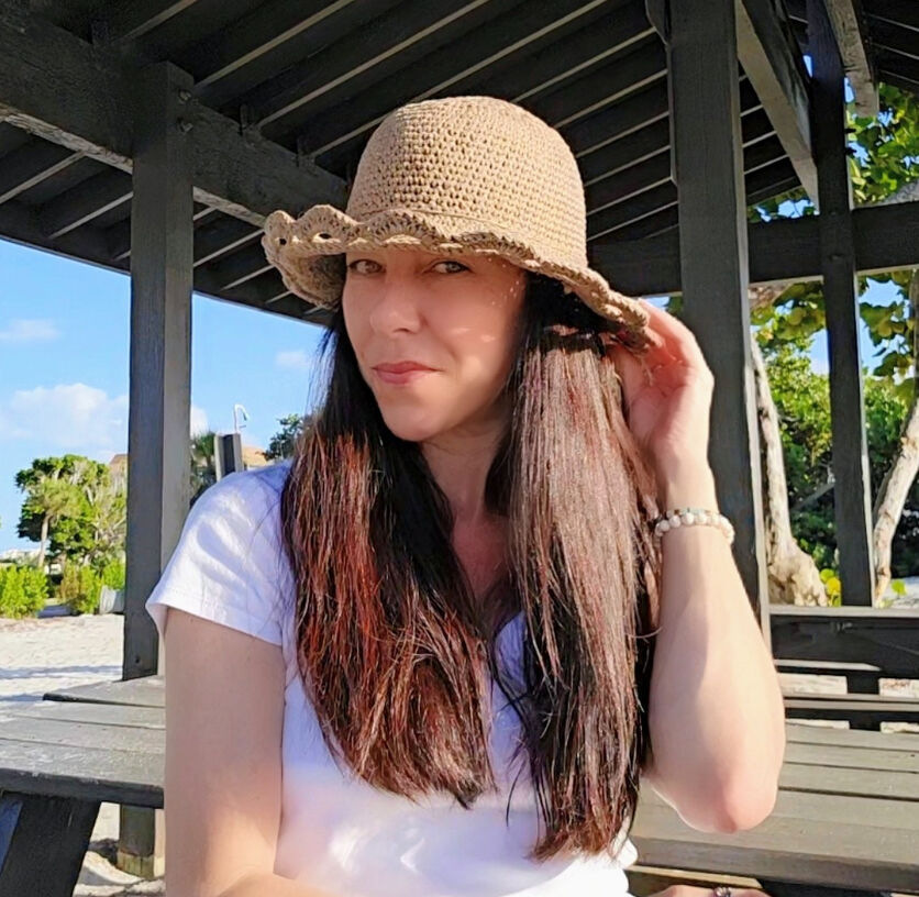 A woman wearing a handmade Radial Bloom crochet sun hat. The hat features a Doily like pattern with a wide brim and provides shade over her face.
