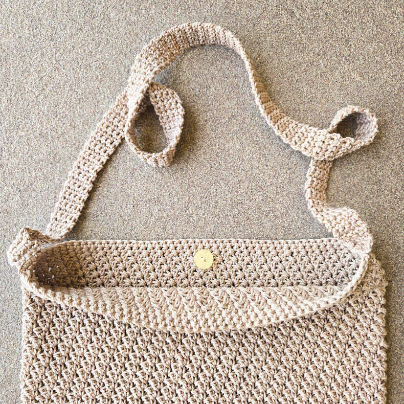 A visual aid on where to place the button and sew it in place on the crochet bag.