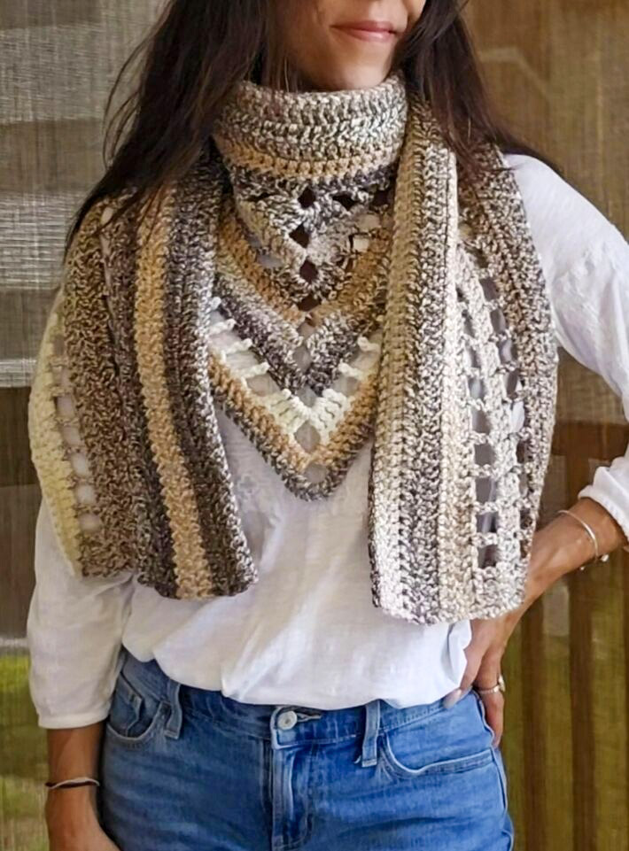 Woman wearing a cozy boho-inspired crochet scarf made with Premier Puzzle yarn in neutral earth tones on a white shirt.